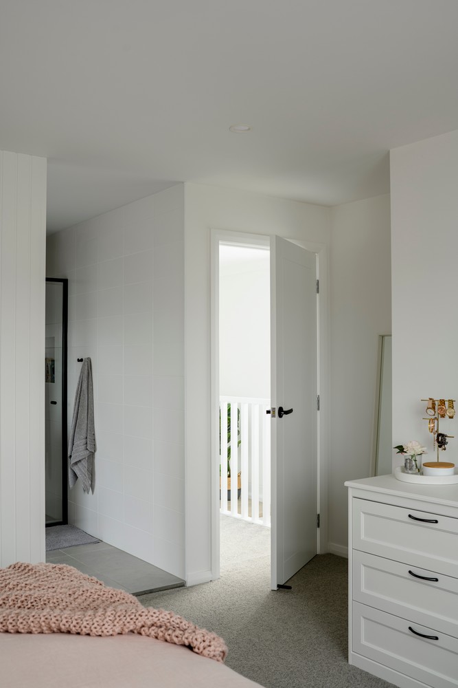 Bright bedroom with a soft, neutral colour palette. A partially open door leads to a hallway, complementing minimalist decor and textures.