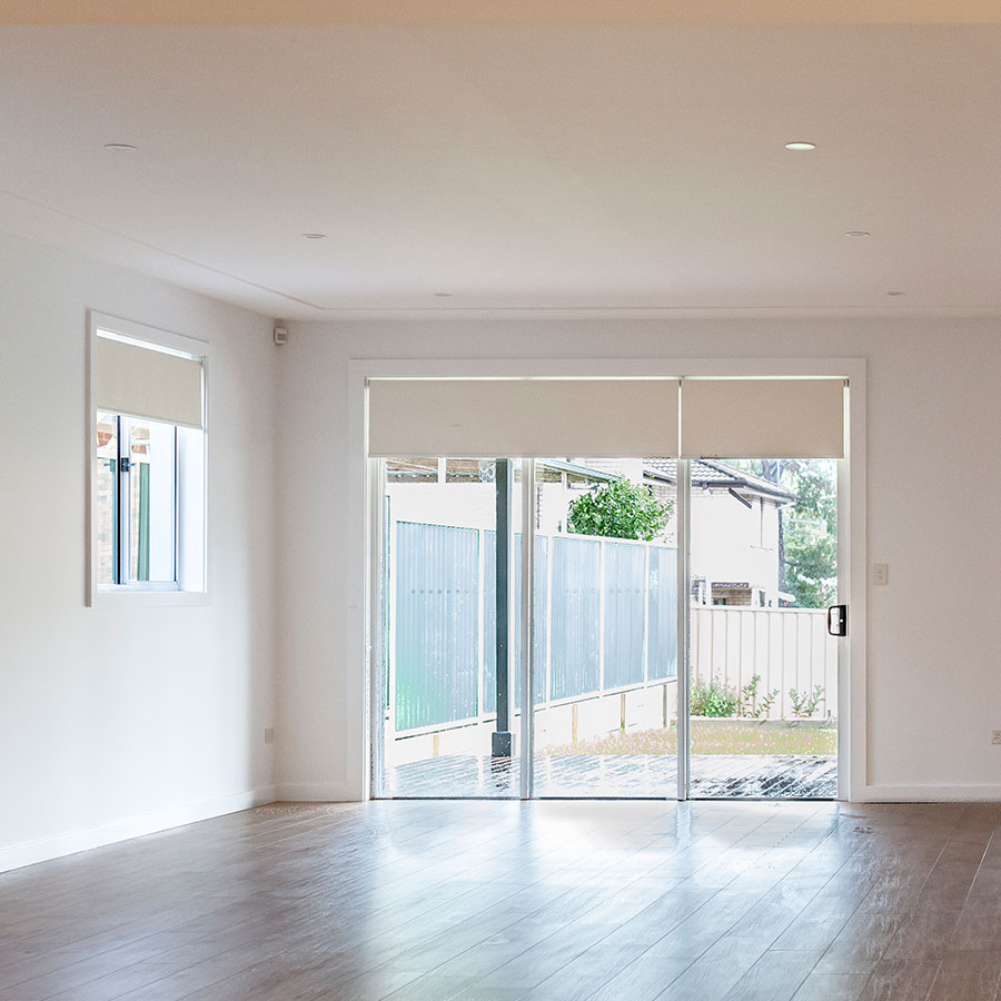 Bright, minimalist living space with large sliding doors leading to an outdoor area, neutral walls, and wooden flooring.