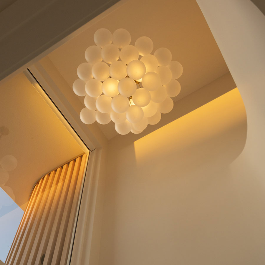 Spherical white pendant light hangs from a sleek ceiling, illuminating a well-designed interior with soft, warm tones.