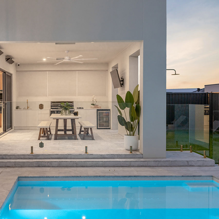 Modern outdoor space featuring a sleek swimming pool, elegant dining area, and minimalist decor, complemented by lush greenery and soft lighting.
