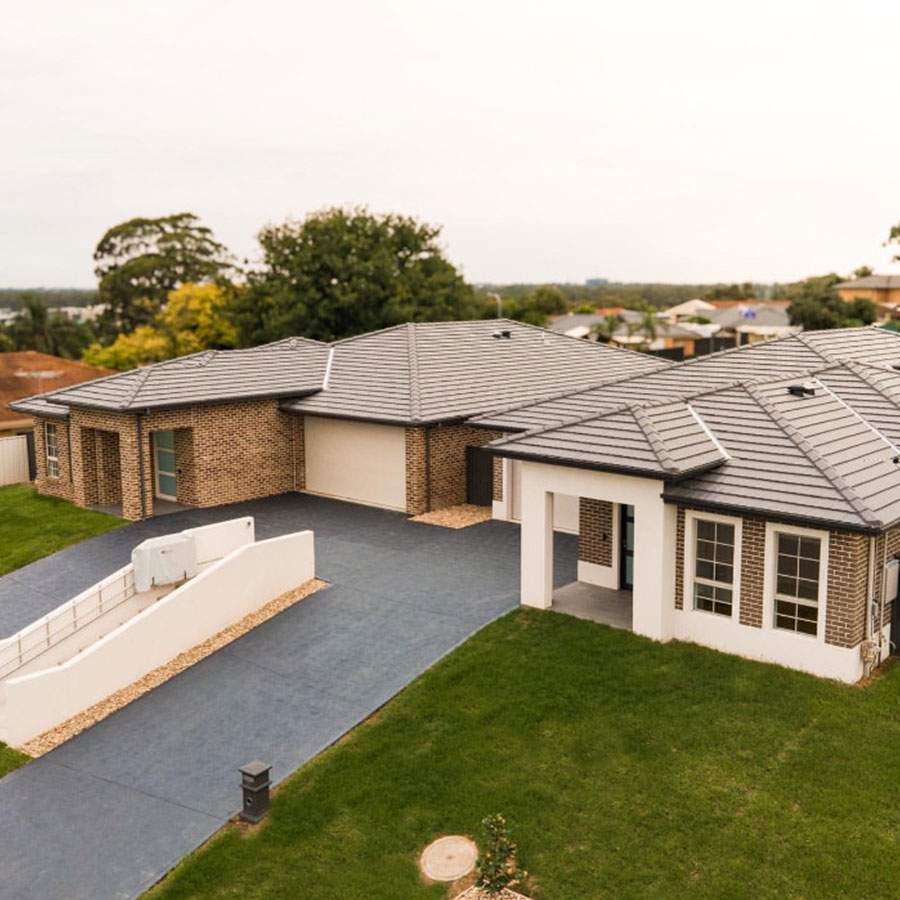 Modern duplex featuring a blend of brick and rendered exterior, grey tiled roof, landscaped lawn, and a structured driveway.