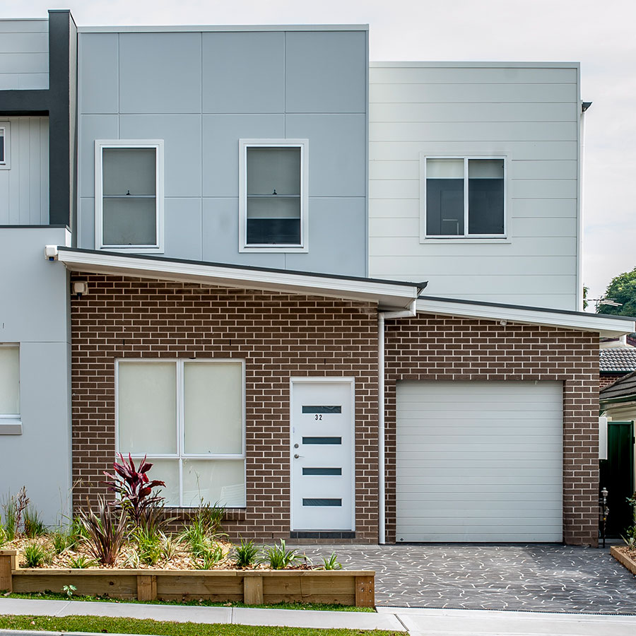 Modern duplex in Gregory Hills featuring a grey and white façade, a brick lower level, and a landscaped front garden.