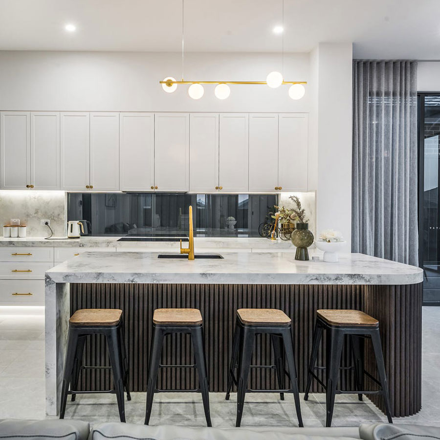 Modern kitchen featuring a marble island with black stools, sleek cabinetry, and a stylish golden light fixture, creating a contemporary feel.