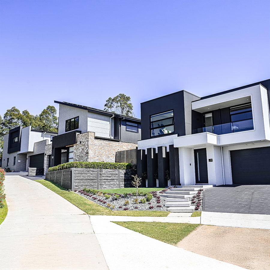 Contemporary homes with sleek lines and contrasting colours, featuring manicured gardens and a clear blue sky in Edmondson Park.